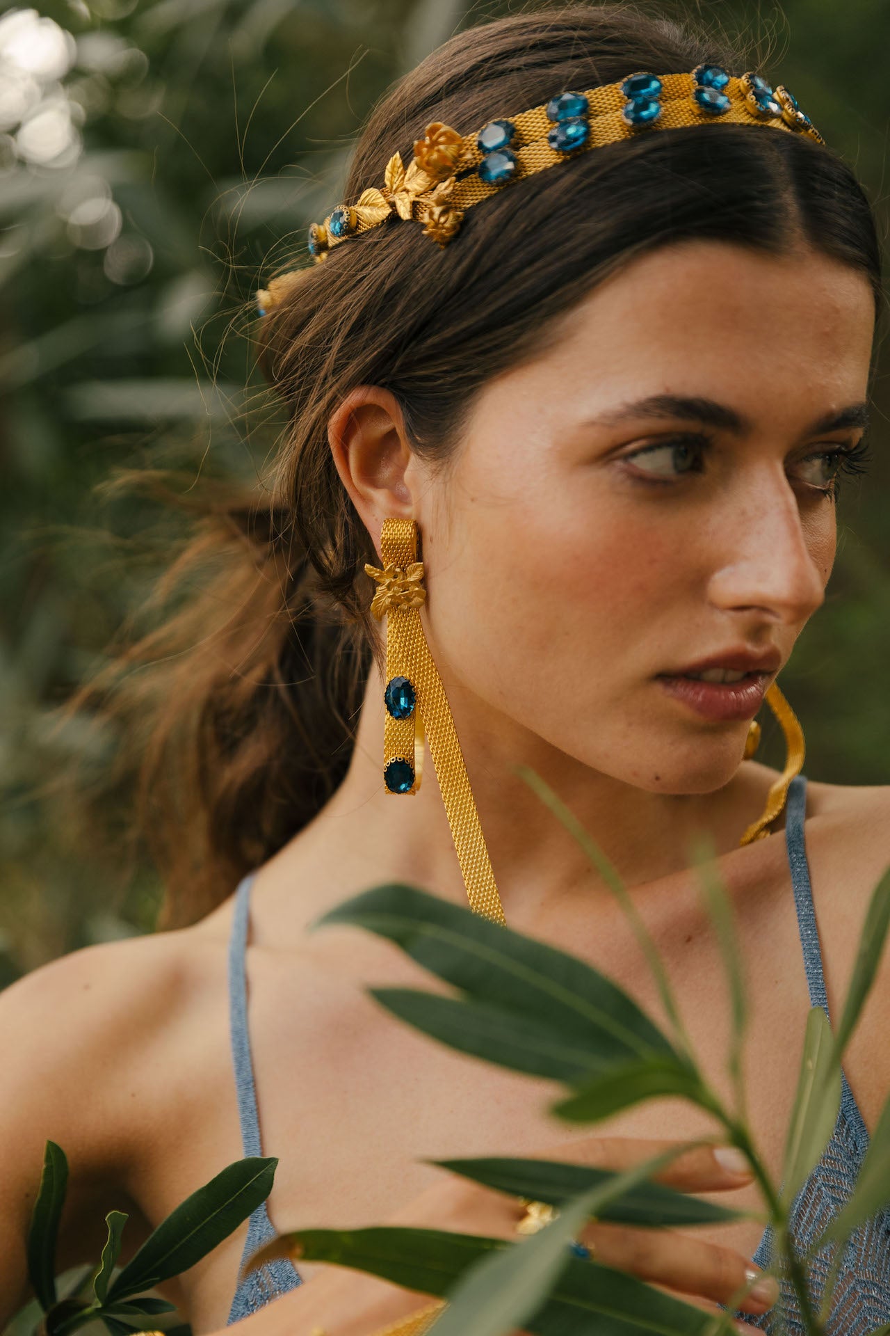 Coroa Lakkos com efeito de fita em latão com pedras azuis e flores em latão banhado a ouro fecho como um laço